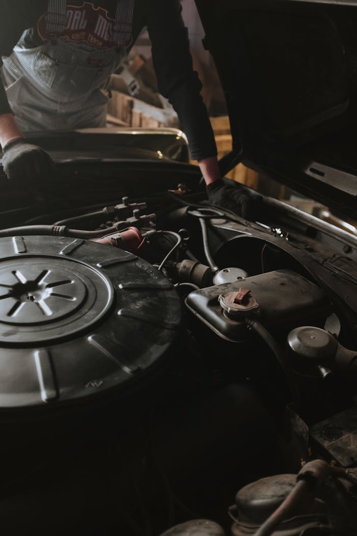 menu-05 Close-up of a mechanic repairing a car engine in a garage setting.
