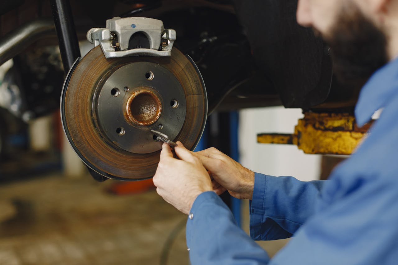 menu-09 Mechanic working on brake disc in an auto repair workshop, close-up, focus on hands.